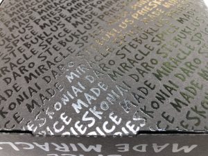 ant matinių tamsių paviršių šriftas ir ornamentika
atspausdinta šilkografijos technologija blizgiu UV laku